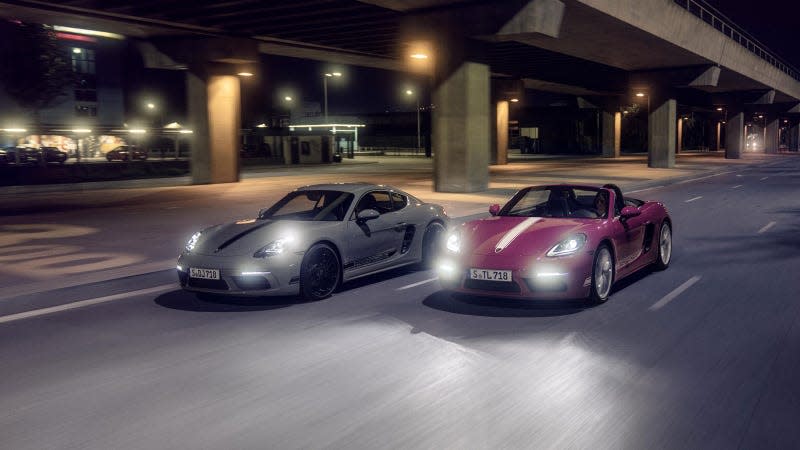 A photo of a grey Porsche Cayman and pink Boxster driving on a dark road. 