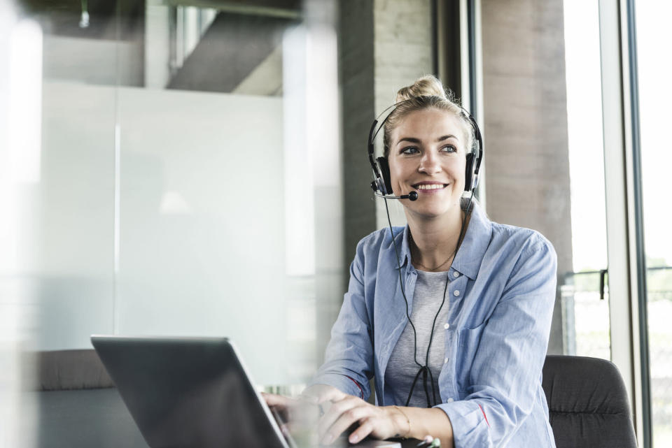 A picture of a woman with a headset and a laptop.
