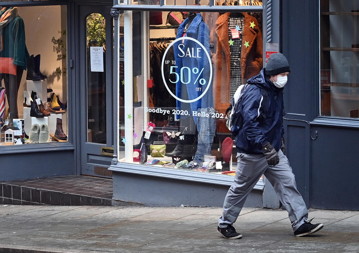 A pedestrian wearing a face mask or covering due to the COVID-19 pandemic, walks past a shop, temporarily closed down due to current coronavirus restrictions, in Shrewsbury, western England on January 6, 2021, on the second day of Britain's national lockdown to combat the spread of COVID-19. - England went back into full lockdown as Europe battled Wednesday to stem a rising tide of coronavirus cases, and the United States logged its worst daily death toll of the pandemic. (Photo by Paul ELLIS / AFP) (Photo by PAUL ELLIS/AFP via Getty Images)