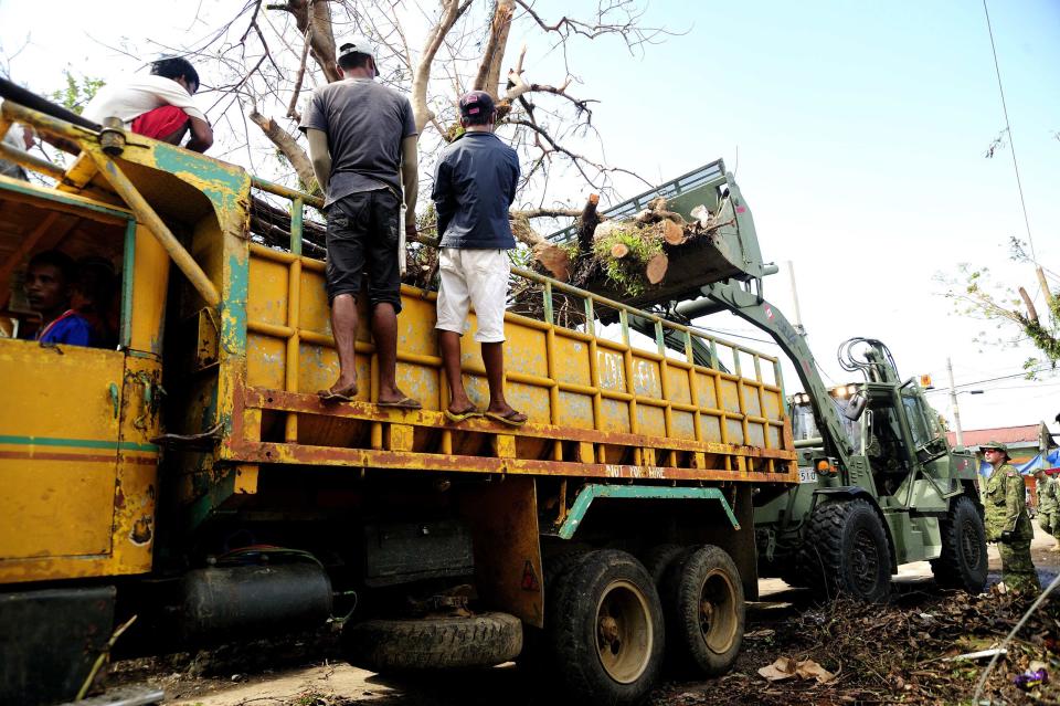 A Canadian Armed Forces Multi Purpose Engineer Vehicle removes fallen branches from the streets in Roxas