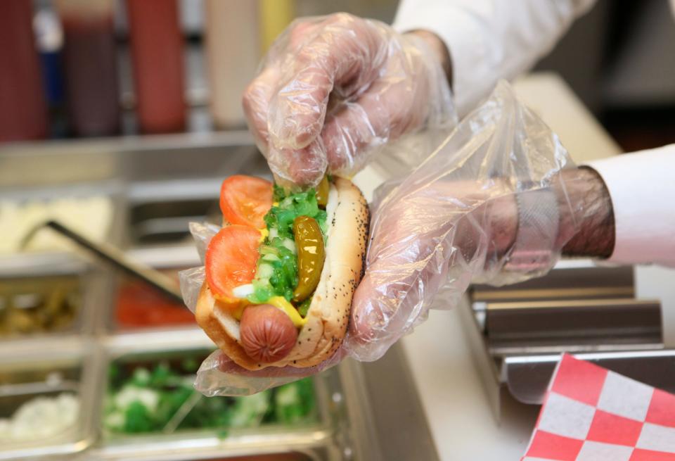 Mazen Muna, owner of Dogg Haus, makes a hotdog for a customer in 2014.