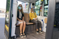 Karin van der Steen, left, and Melanie Way, both of Falls Church, Va., board the Relay, an electric autonomous vehicle, in Fairfax, Va., Thursday, Oct. 22, 2020. The future of transportation arrived in northern Virginia, looking like a big blue toaster on wheels that can seat six and drive itself through the region’s notorious traffic. State and local officials debuted the Relay system Thursday, an all-electric, autonomous vehicle that will provide free shuttle rides back and forth from the Dunn Loring Metrorail stop to the bustling Mosaic District in Fairfax County, Va. (AP Photo/Jacquelyn Martin)