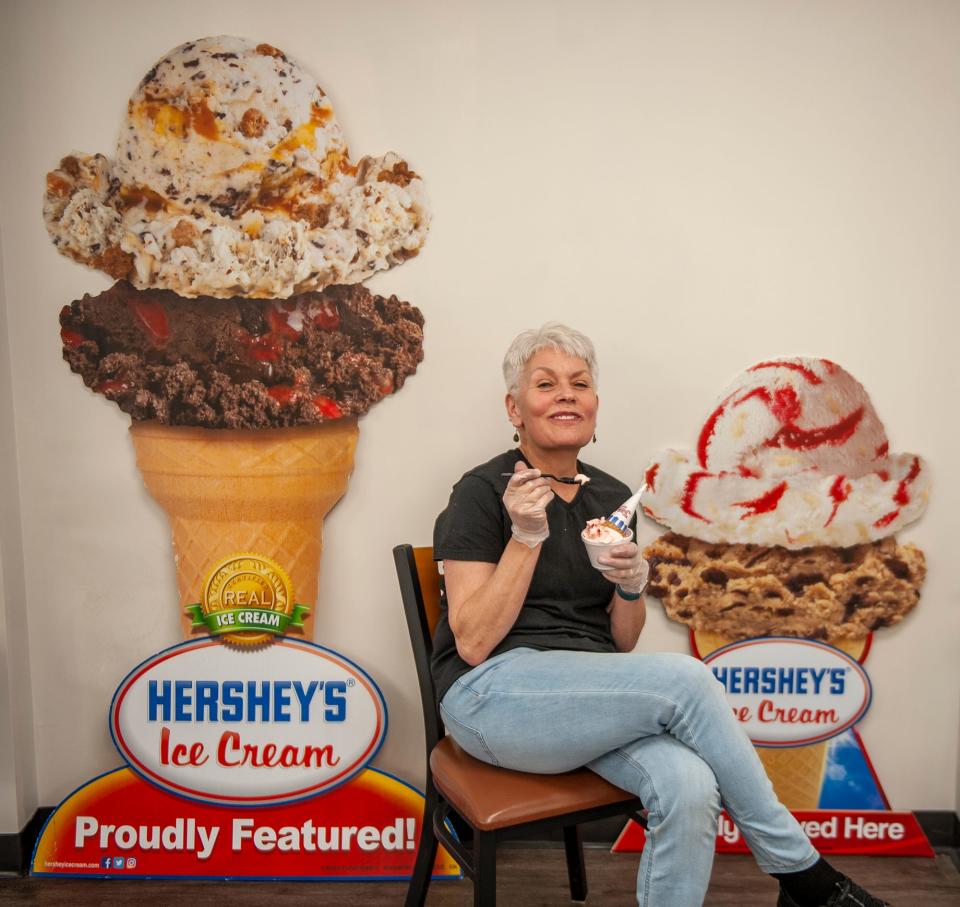 Tina Chemini, owner of T.C. Scoops, enjoys an ice cream inside her new store in Holliston, April 19, 2023. Chemini previously ran T.C. Scoops in Medway from 2011 to 2021.
