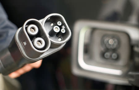FILE PHOTO: A man holds DC-power charging plug of his BMW i3 electric car during the presentation of a new super-fast multi-charging power column "comfort charge" belonging to Germany's telecommunications company Deutsche Telekom AG at Telekom's headquarters in Bonn, Germany November 5, 2018. REUTERS/Wolfgang Rattay/File Photo