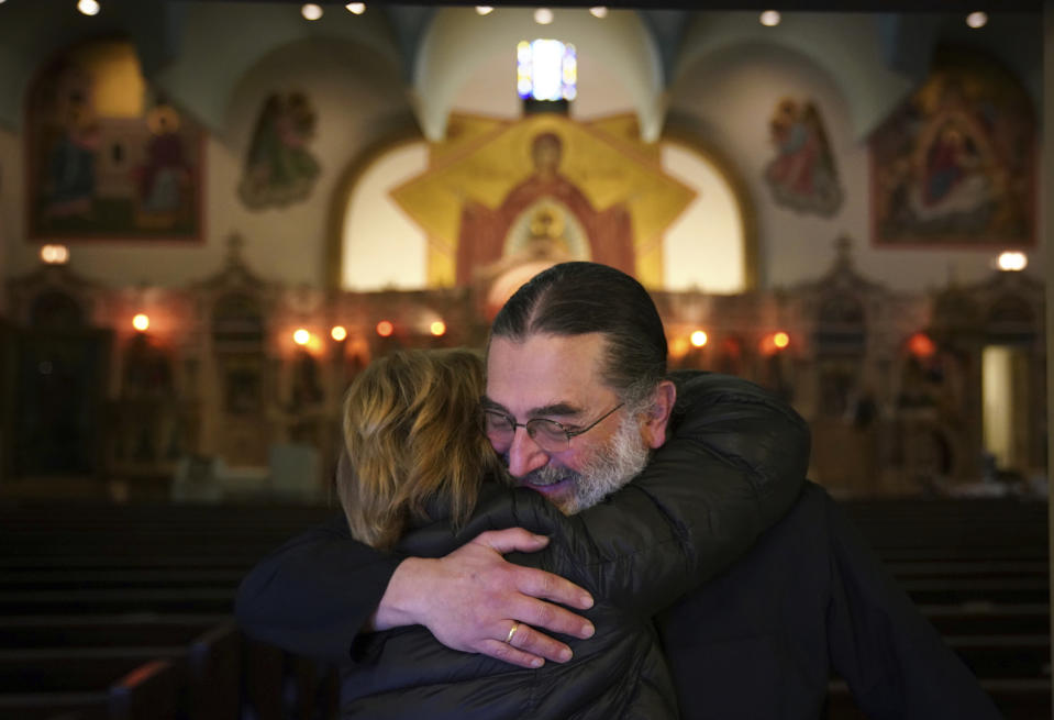 Rev. Nicholas Jonas hugs a longtime parishioner of Holy Trinity Greek Orthodox Church, which avoided being sold at auction, Friday, Dec. 14, 2018, in Chicago. The 120-year-old Chicago church was saved from auction after a midnight call from a group of donors, which one church official said was "a Christmas miracle." (E. Jason Wambsgans/Chicago Tribune via AP)