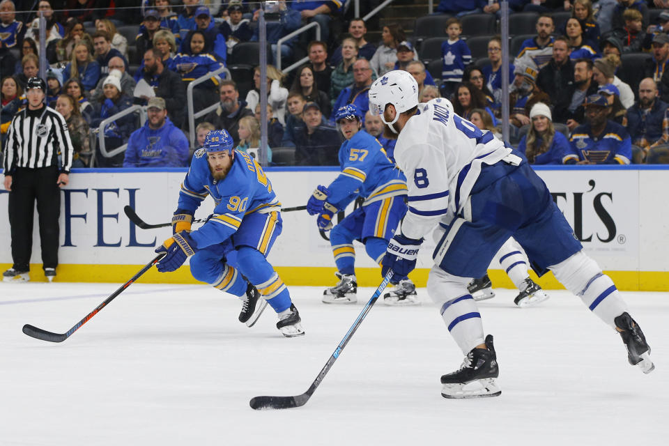 Toronto Maple Leafs' Jake Muzzin (8) looks to pass the puck as he is defended by St. Louis Blues' Ryan O'Reilly (90) during the second period of an NHL hockey game Saturday, Dec. 7, 2019, in St. Louis. (AP Photo/Billy Hurst)