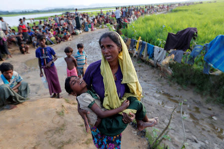 A Rohingya refugee woman who crossed the border from Myanmar a day before, carries her daughter and searches for help as they wait to receive permission from the Bangladeshi army to continue their way to the refugee camps, in Palang Khali, Bangladesh October 17, 2017. REUTERS/Jorge Silva