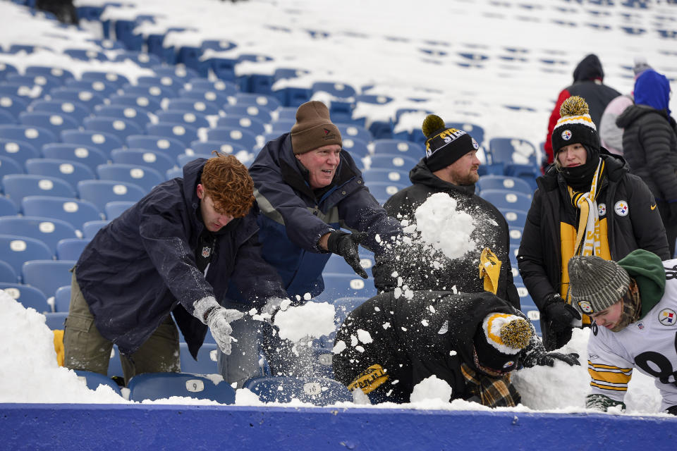Football fans clear snow from their seats before an NFL wild-card playoff football game between the Buffalo Bills and the Pittsburgh Steelers, Monday, Jan. 15, 2024, in Buffalo, N.Y. (AP Photo/Adrian Kraus)