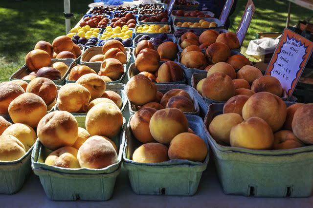 <p>VO IMAGES / Getty Images</p> Organic peaches in a farmers market.