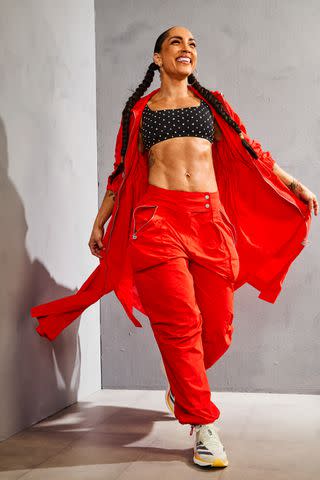 <p>Jess Juliao</p> Bra: Brittany Allen Dream Rhinestone Square Neck Bralette in Black. Jacket: GSTQ Nylon Parachute Anorak in Deep Orange. Bottoms: GSTQ Nylon Parachute Pants in Deep Orange. Shoes: Adidas Adizero Takumi Sen 10. Jewelry: Robin’s Own