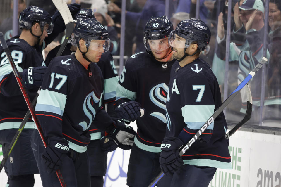 Seattle Krakenleft wing Andre Burakovsky (95) is joined by center Jaden Schwartz (17) and right wing Jordan Eberle (7) after scoring against the Carolina Hurricanes during the second period of an NHL hockey game, Monday, Oct. 17, 2022, in Seattle. (AP Photo/John Froschauer)