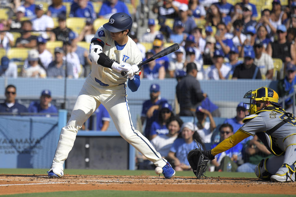 Los Angeles Dodgers' Shohei Ohtani, left, his hit by a pitch as Milwaukee Brewers catcher William Contreras catches during the second inning of a baseball game Saturday, July 6, 2024, in Los Angeles. (AP Photo/Mark J. Terrill)