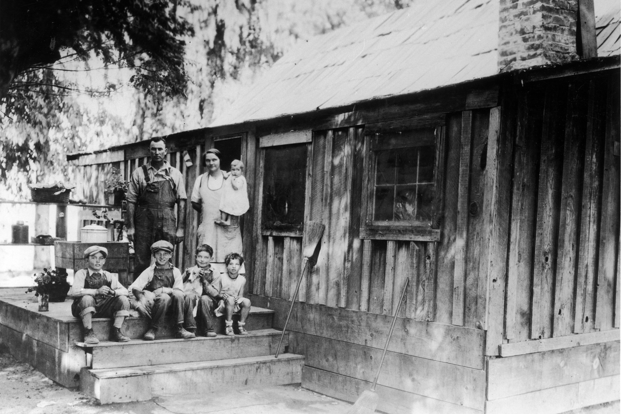 A family pose on the steps of their home during the Great Depression, location unknown, USA