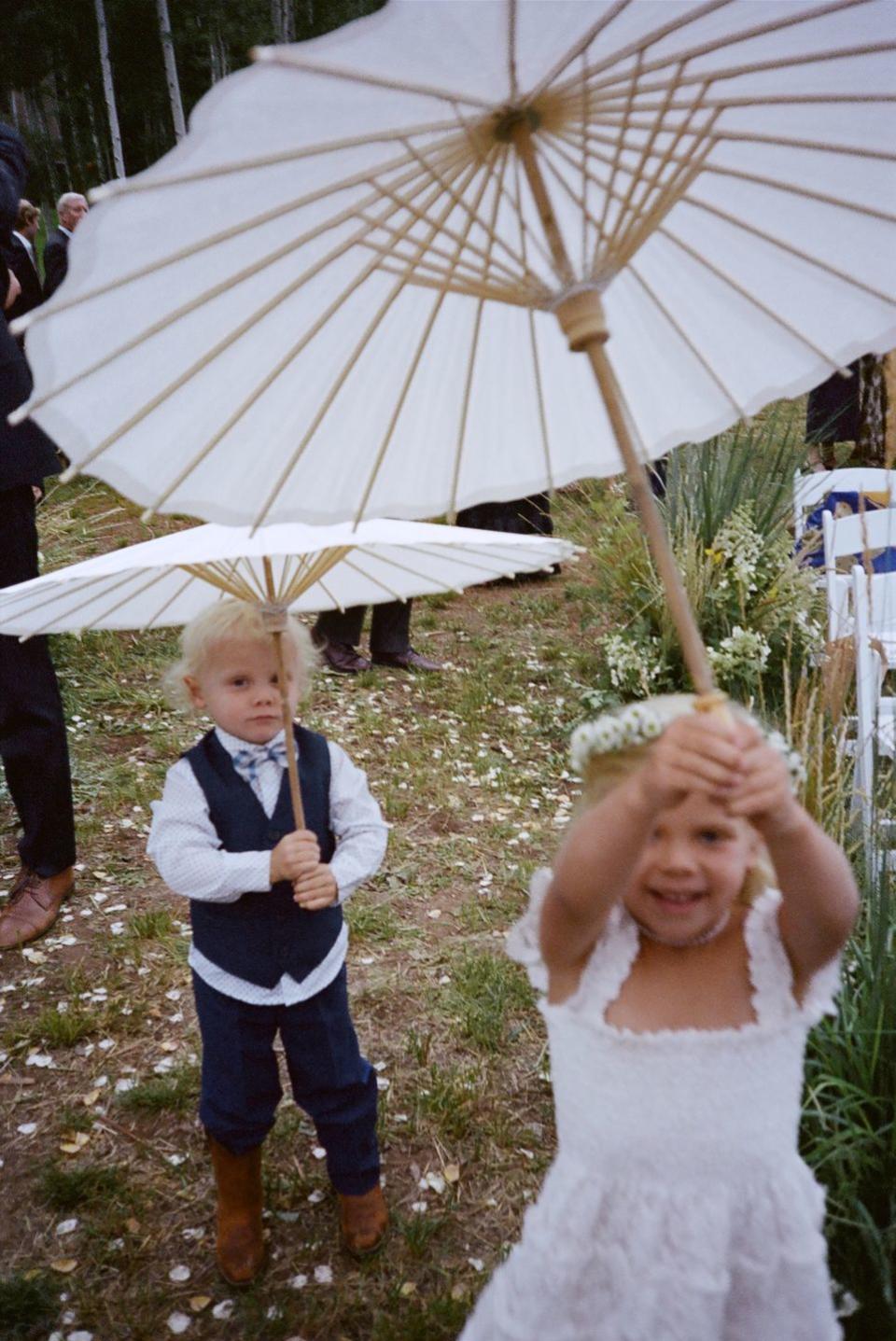 a couple of children stand under an umbrella