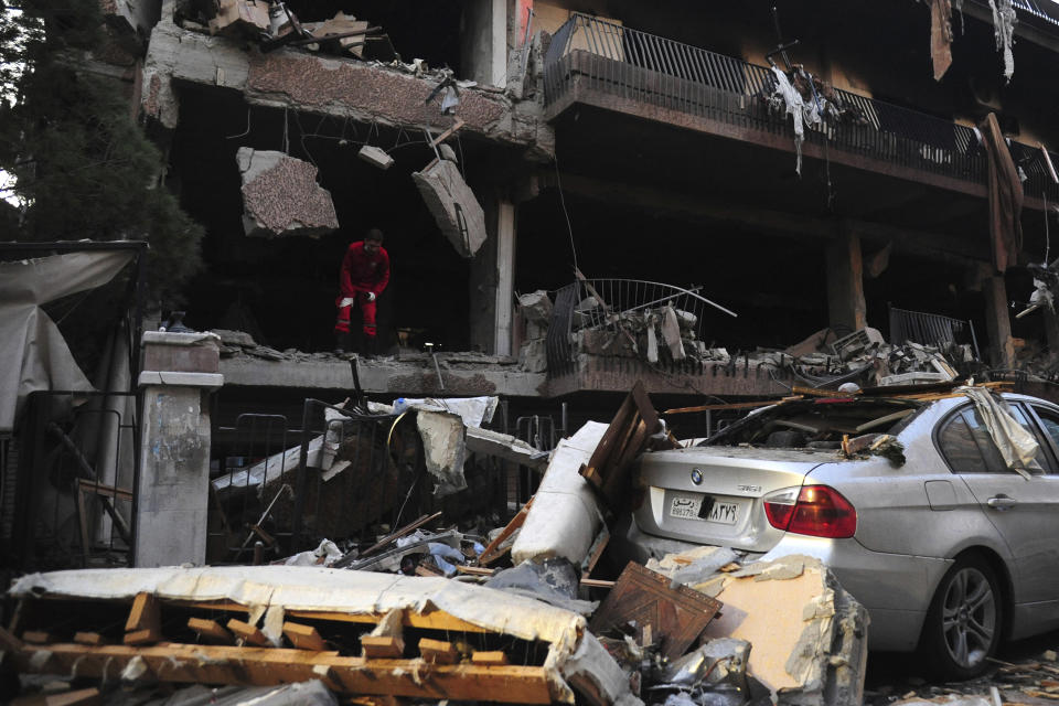 In this photo released by the Syrian official news agency SANA, a Syrian official checks the damage of a building targeted by Israeli missile strikes in the early morning in the Mezzeh area in the capital Damascus, Syria, Tuesday, Nov. 12, 2019. Syria's state-run news agency says Israel has struck a residential building in Damascus housing a commander of the Palestinian Islamic Jihad group with two missiles, killing two people. (SANA via AP)