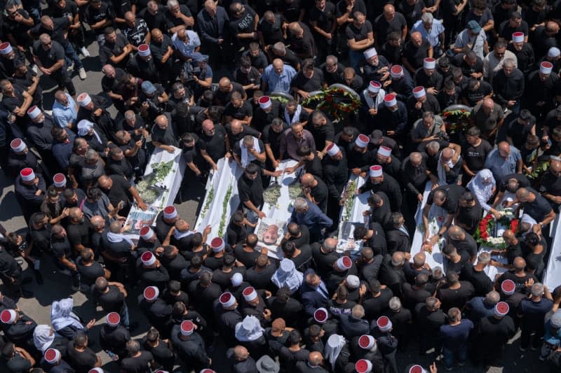 People mourn at the funeral of their relatives in the Druze town of Majd al-Shams in the Israeli-controlled Golan Heights. Several children and young people were killed in a rocket attack on a football field in the village. Ilia Yefimovich/dpa