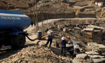 A resident of Nueva Union shantytown buys water from a tanker truck in Villa Maria del Triunfo district of Lima, Peru, May 7, 2018. REUTERS/Mariana Bazo