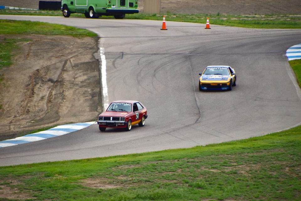 A Pontiac 1000 leads a Pontiac Fiero through the final turn at High Plains Raceway
