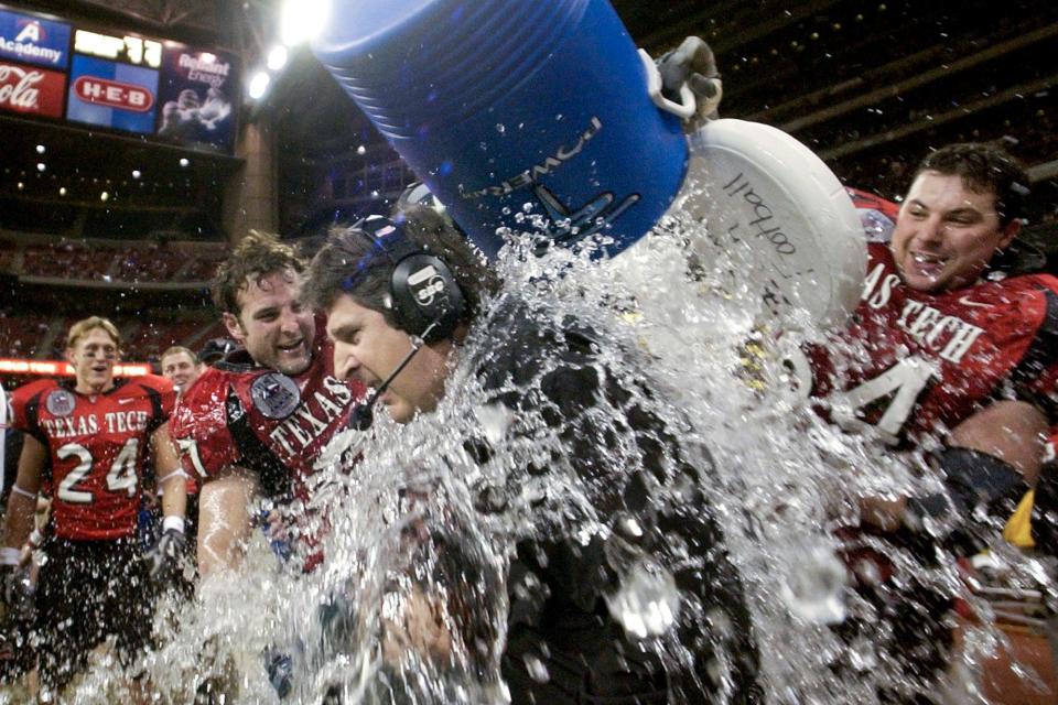 FILE - Texas Tech coach Mike Leach, center, is dunked with water by Wes Welker (27), left, and Cody Campbell (64) right during the final minutes against Navy in the Houston Bowl on Dec. 30, 2003 in Houston. Of the top 25 most-prolific passing seasons in major college football history by yards per game, 12 have direct connections to Hal Mumme and Leach -- from Kentucky to Houston to Texas Tech to New Mexico State to Washington State. (AP Photo/David J. Phillip, File)