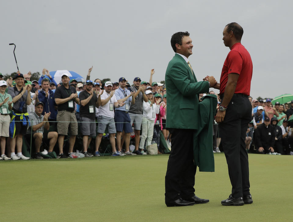 Patrick Reed helps Tiger Woods with his green jacket after Woods won the Masters golf tournament Sunday, April 14, 2019, in Augusta, Ga. (AP Photo/Charlie Riedel)