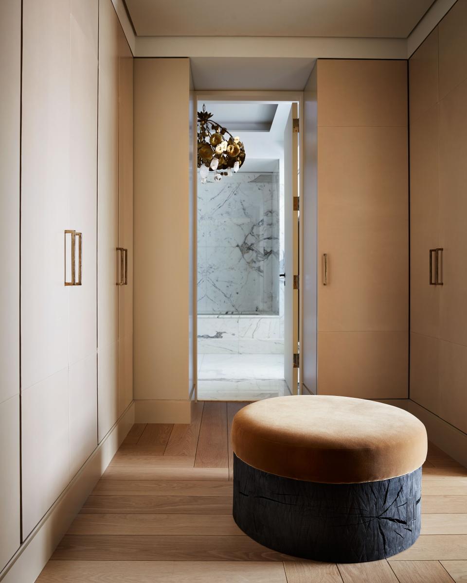 A circular ottoman with a blackened oak base and mustard velvet cushion, designed by Yovanovitch, anchors a corner of the main suite. It was made specifically for the space. Beyond is the marble-clad main bath and its pièce de résistance: a 1970s “Nénuphars” chandelier by Robert Goossens, made of brass, bronze, and rock crystal.