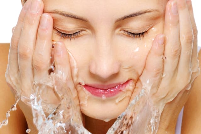 Cute woman wash her  face with water