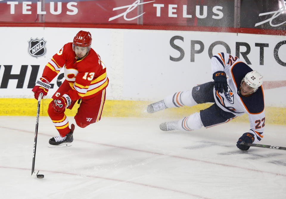 Calgary Flames' Johnny Gaudreau (13) gets the puck away from Edmonton Oilers' Tyson Barrie (22) during the second period of an NHL hockey game, Friday, Feb. 19, 2021 in Calgary, Alberta. (Todd Korol/The Canadian Press via AP)