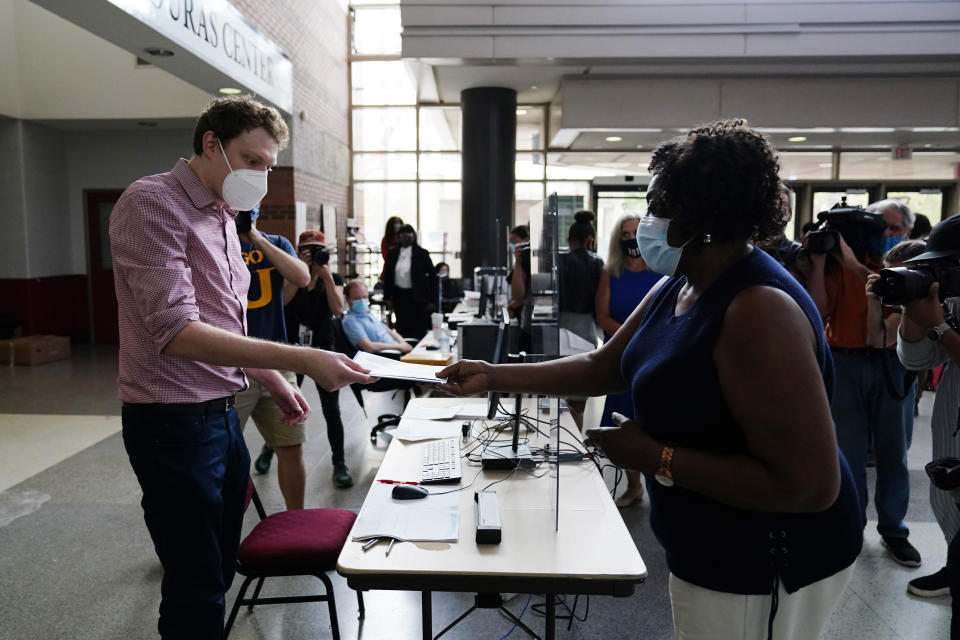 Philadelphia resident Priscilla Bennett receives her mail-in ballot at the opening of a satellite election office at Temple University's Liacouras Center, on Sept. 29, 2020, in Philadelphia. Pennsylvania is one of this year's most hotly contested battleground states and also is facing a flurry of lawsuits, complaints and partisan finger-pointing over its election procedures and systems. (AP Photo/Matt Slocum)