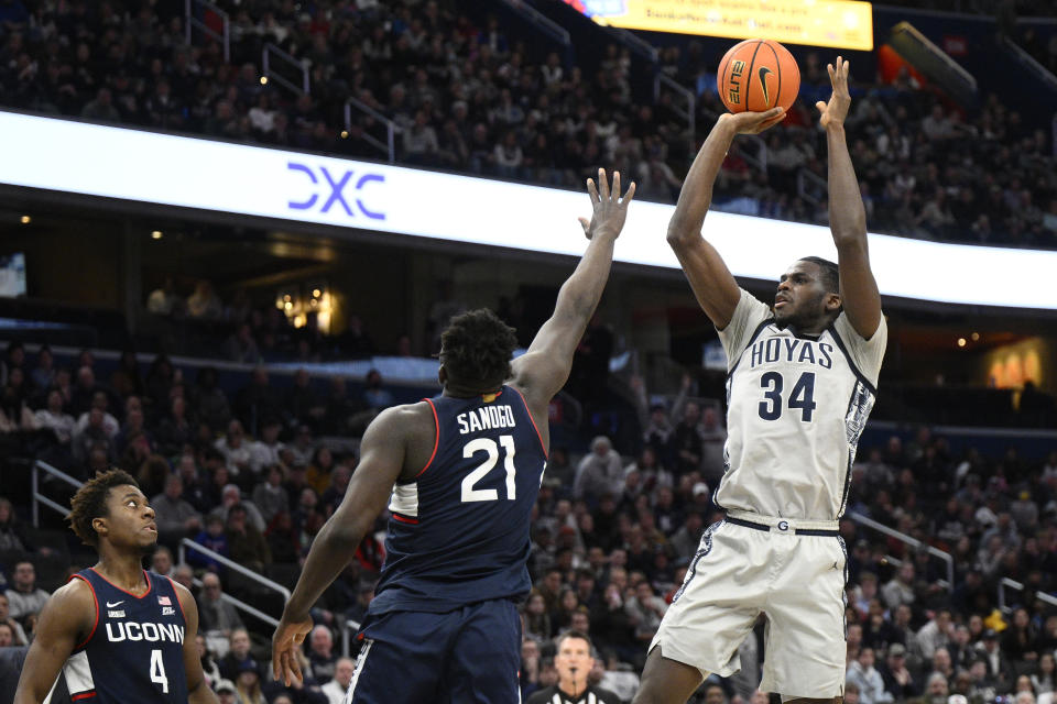 Georgetown center Qudus Wahab (34) shoots against Connecticut forward Adama Sanogo (21) and guard Nahiem Alleyne (4) during the second half of an NCAA college basketball game, Saturday, Feb. 4, 2023, in Washington. Connecticut won 68-62. (AP Photo/Nick Wass)