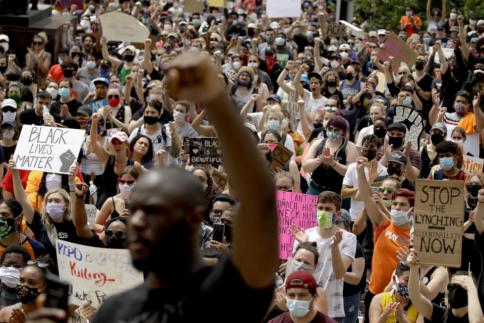 People hold signs as they listen to a speaker in front of city hall in downtown Kansas City, Mo., Friday, June 5, 2020, during a rally to protest the death of George Floyd who died after being restrained by Minneapolis police officers on May 25. (AP Photo/Charlie Riedel)