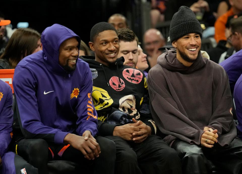 Phoenix Suns forward Kevin Durant (left) and guards Bradley Beal (center) and Devin Booker watch their team play against the San Antonio Spurs during the second quarter at Footprint Center in Phoenix on Oct. 31, 2023.