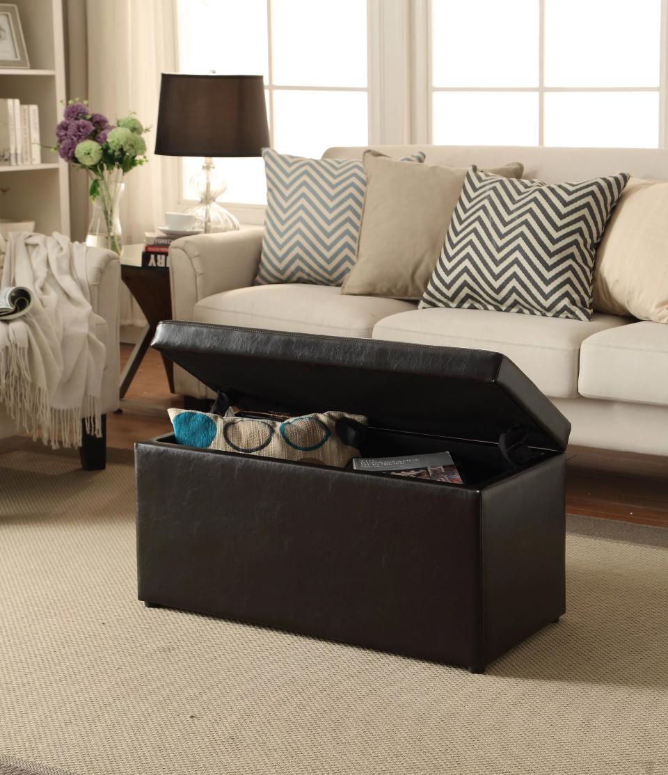 a black storage ottoman holding a pillow and coffee books