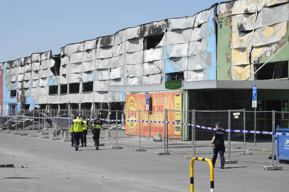Police walks by a temporary fence put up to block access to a burnt-down shopping center in Warsaw, Poland, on Wednesday, May 15, 2024. A weekend fire at the Marywilska 44 shopping center dealt tragedy to many members of Poland's Vietnamese community. People lost entire livelihoods and say they don't know how they will manage to make a living. (AP Photo/Czarek Sokolowski)
