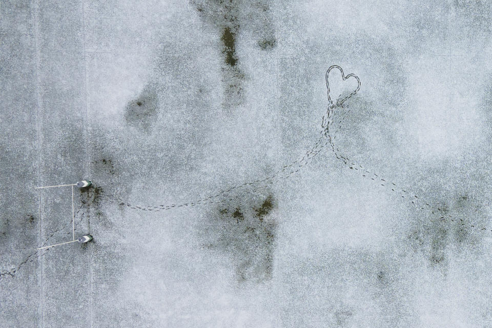 Huellas crean una silueta de corazón en un campo de rugby cubierto de nieve, en Santiago, Chile, el 8 de mayo de 2024. (AP Foto/Matías Basualdo)