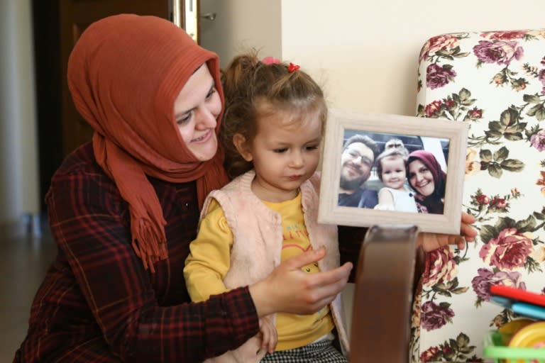 Sümeyye Yilmaz, avec sa fille, montre une photo de famille où l'on voit son mari Mustafa Yilmaz, disparu pendant huit mois, le 21 novembre 2019 à Ankara
