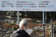 A man wearing a face mask walks past a banner showing precautions against the coronavirus in Seoul, South Korea, Monday, Nov. 23, 2020. (AP Photo/Lee Jin-man)