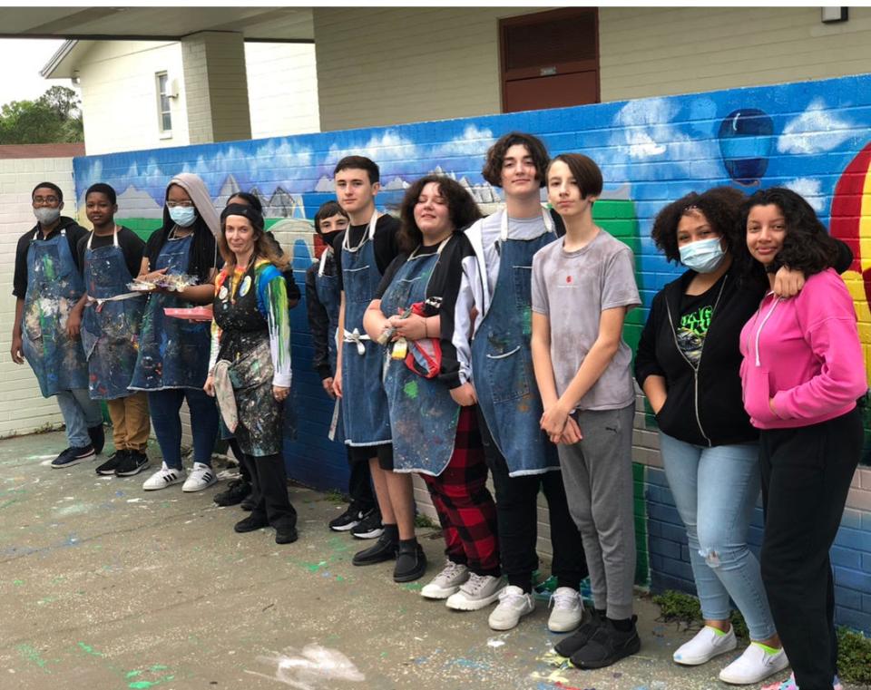 Lake Weir Middle School art students have been working on murals at the school. Among the students participating are, left to right, Jacob Johnson, Rayvon Bell, Dankeria Robinson, Keenyah Paddyfote (behind the teacher, Lisa Russo), Logan King, Caleb Young, Novah Haynes Ungerathen, Lucas Toste, Mason Hartley, Neveah Mike and Crista Alvarado. The work started in January and is almost complete. The mural is of the past (Versailles garden-like scene), present (hot air balloons,) and future (space landscape.) Many students would work on the murals during their own time, including before school and lunch periods.