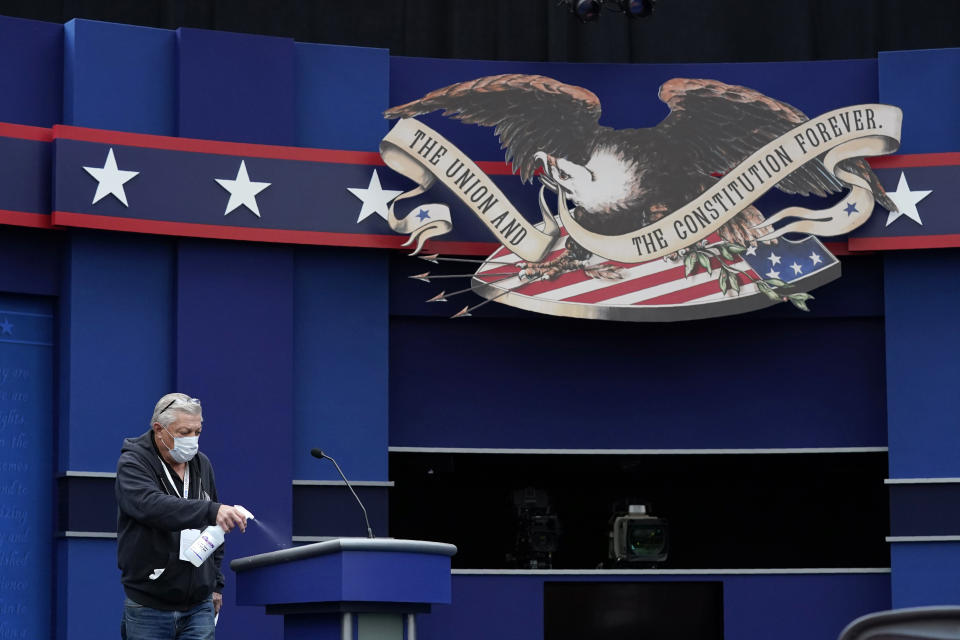 A worker sprays sanitizer on a lectern as preparations take place for the first Presidential debate in the Sheila and Eric Samson Pavilion, Monday, Sept. 28, 2020, in Cleveland. The first debate between President Donald Trump and Democratic presidential candidate, former Vice President Joe Biden is scheduled to take place Tuesday, Sept. 29. (AP Photo/Patrick Semansky)