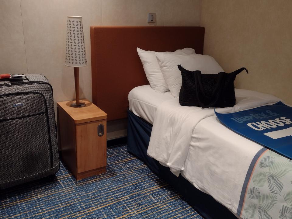 A twin-size cruise bed with a small nightstand and a suitcase next to it.