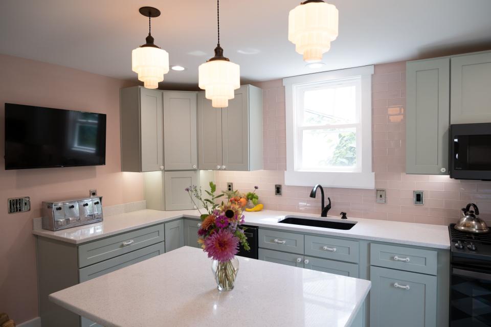 White vintage-style knobs and pulls echo the milk glass scalloped pendant lights glowing softly above the island, while whimsical vintage and retro-style flourishes dot the room in this renovated kitchen in Louisville's Clifton neighborhood.