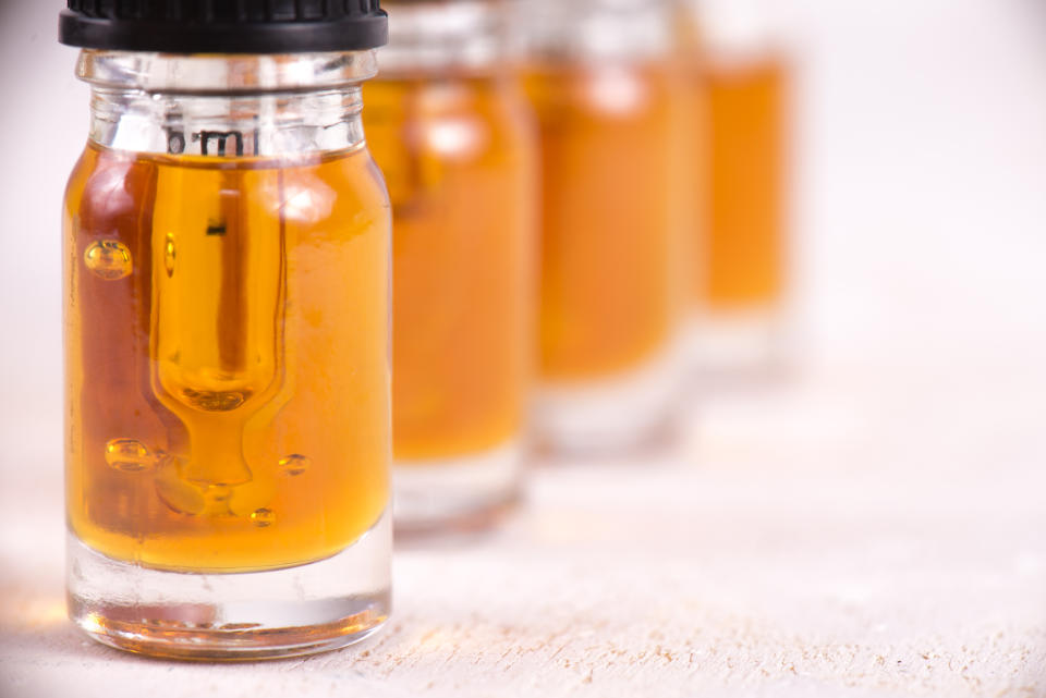 Four vials of cannabidiol liquid lined up on a counter.