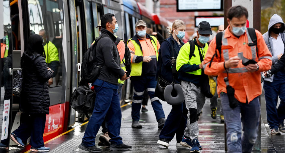 A group of masked workers exit a tram in Sydney's CBD. 