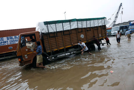 People push a stranded truck in a waterlogged highway after heavy rains in Gurugram, previously known as Gurgaon, on the outskirts of New Delhi, India, July 29, 2016. REUTERS/Adnan Abidi