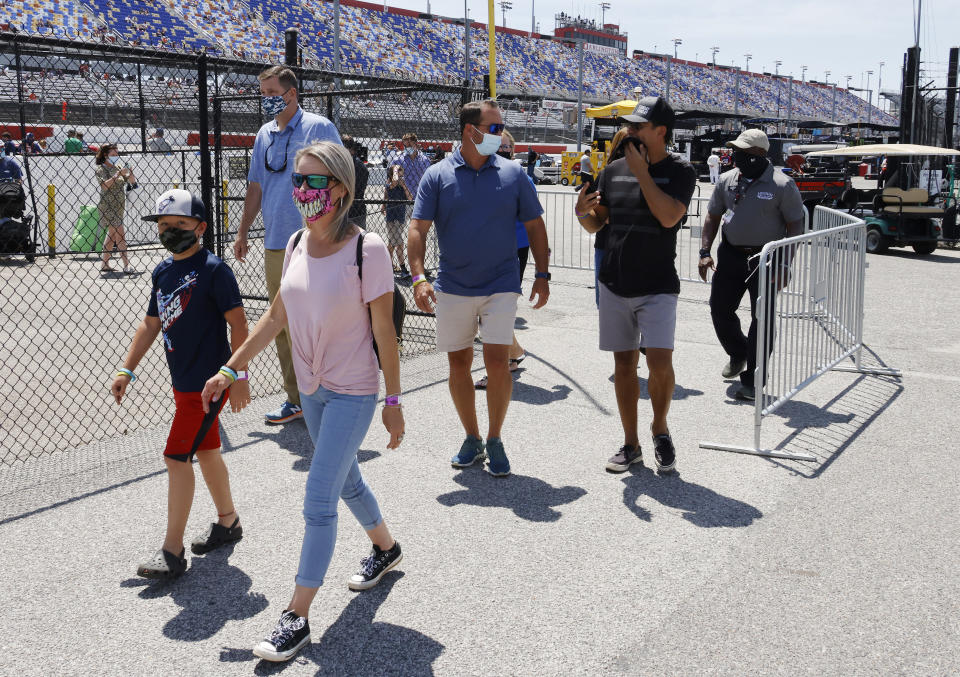 Fans walk through the garage area before a NASCAR Cup Series auto race at Darlington Raceway, Sunday, May 9, 2021, in Darlington, S.C. It is the first time this year that fans are allowed back in the garage area. (AP Photo/Terry Renna)