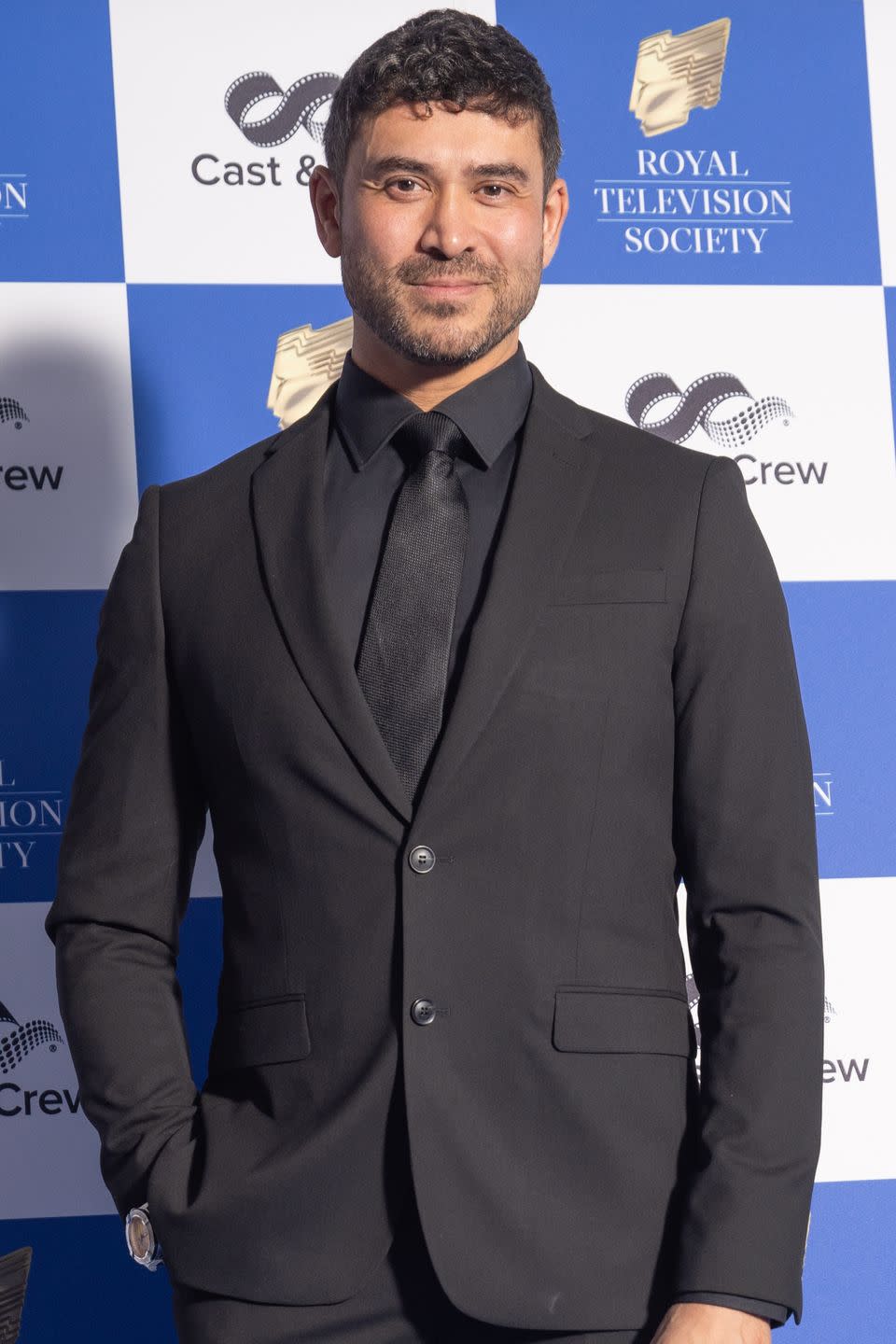 rav wilding on a red carpet in a very sharp black suit
