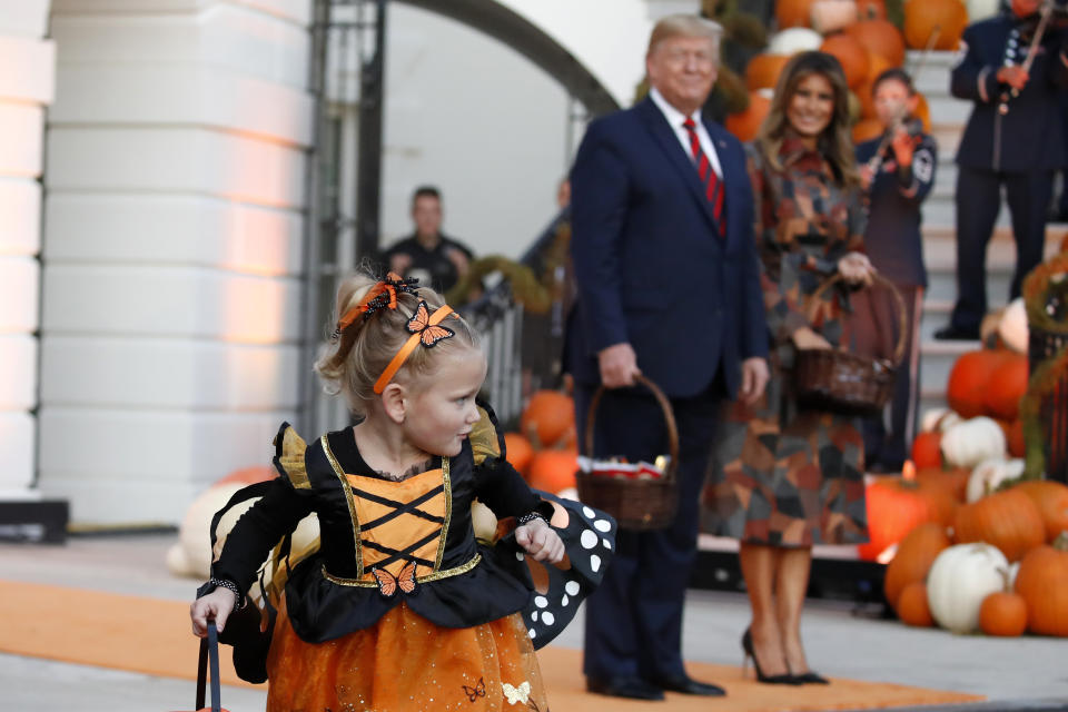 President Donald Trump and first lady Melania Trump watch a young girl as they give candy to children during a Halloween trick-or-treat event on the South Lawn of the White House which is decorated for Halloween, Monday, Oct. 28, 2019, in Washington. (AP Photo/Alex Brandon)