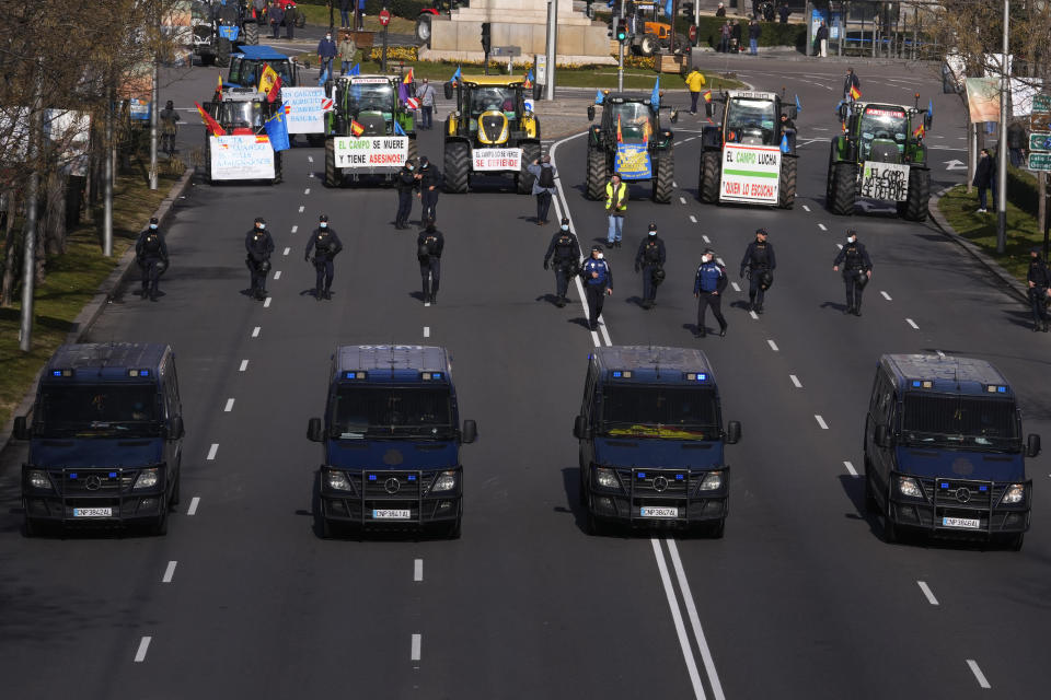 Police escort protesters in tractors during a protest march down the Castellana Boulevard in defence of Spanish rural areas in Madrid, Spain, Sunday, Jan. 23, 2022. Members of rural community are demanding solutions by the government for problems and crisis in the Rural sector. (AP Photo/Paul White)