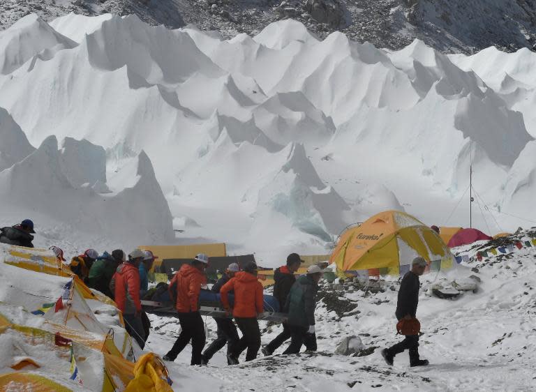 Rescue team personnel carry an injured person towards a waiting rescue helicopter at Everest Base Camp on April 26, 2015, a day after an avalanche triggered by an earthquake devastated the camp