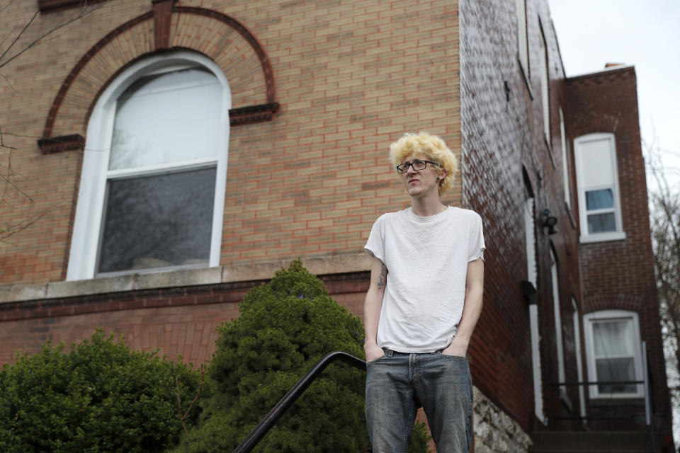 In this Saturday, March 28, 2020 photo, Kyle Kofron poses for a photo outside his home in St. Louis. Kofron still has his job at an ice cream factory, but his three roommates are suddenly unemployed due the the coronavirus pandemic. Kofron is advocating for a rent strike during the outbreak saying it may be their only option. (AP Photo/Jeff Roberson)