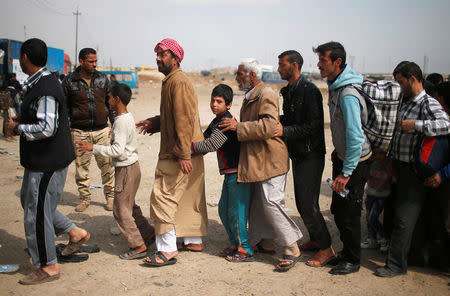 Displaced residents who fled their homes wait to be searched by Iraqi troops as Iraqi forces battle with Islamic State militants, in western Mosul, Iraq March 28, 2017. REUTERS/Suhaib Salem